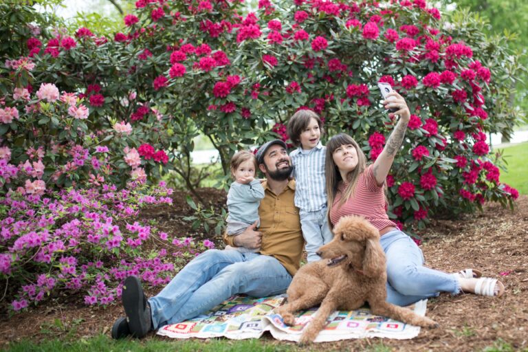 Family of four taking a picture in front of the rhododendrons.