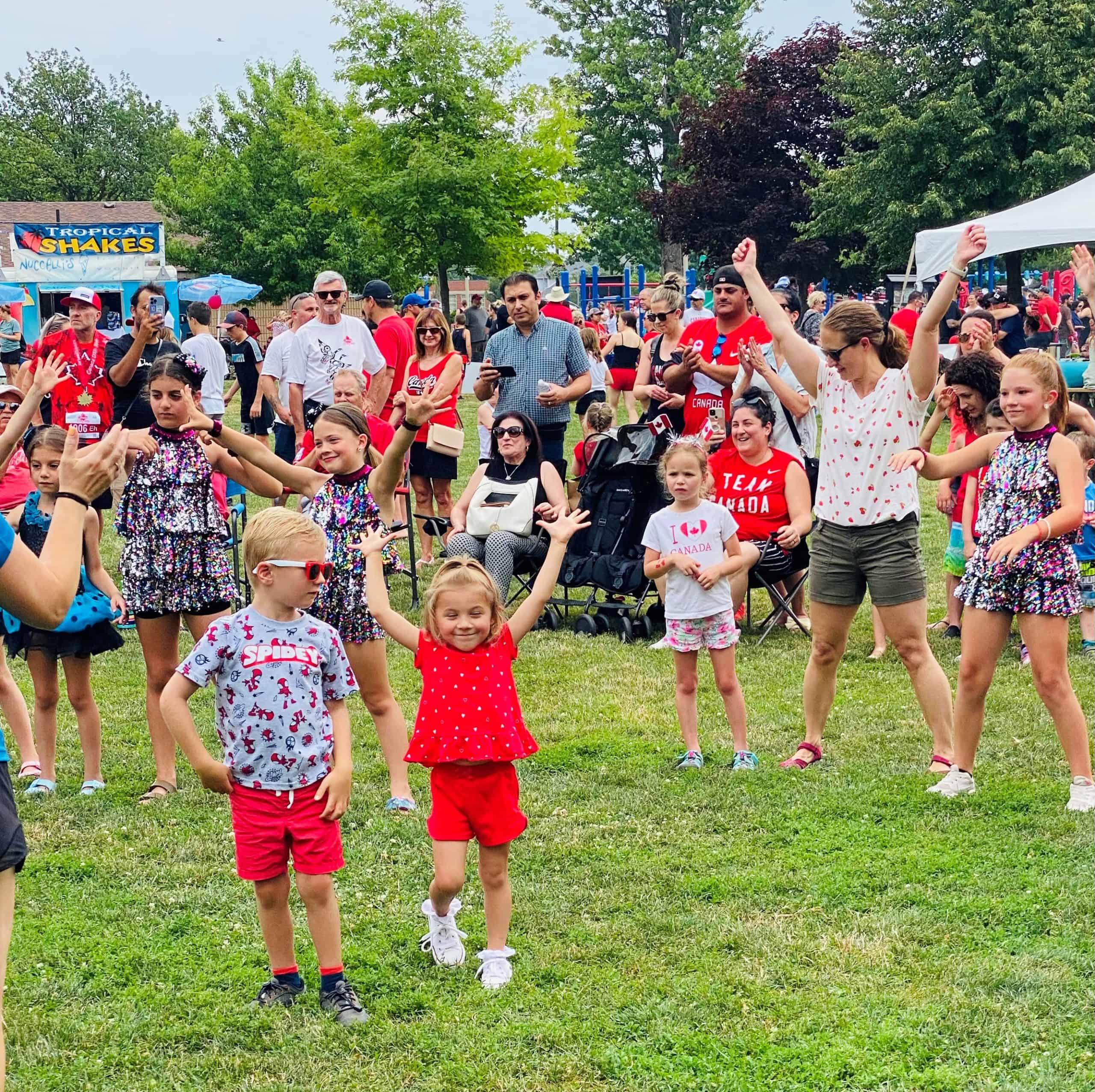Children and parents dance in the park on Canada Day.