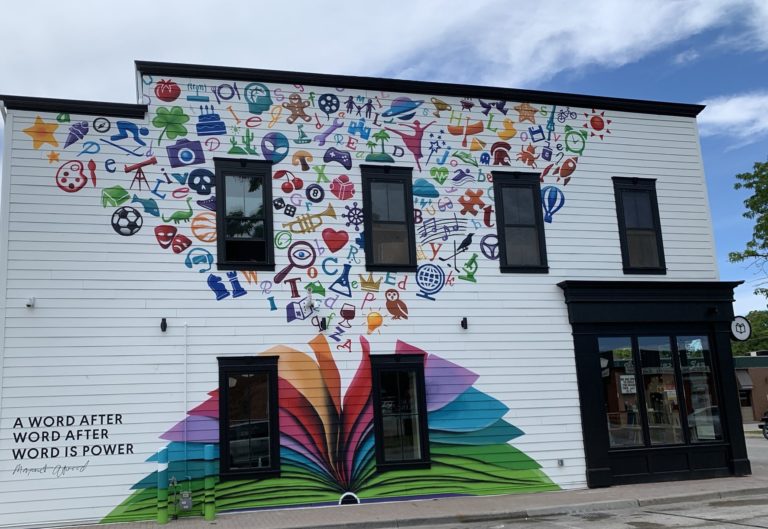 <p>River Bookshop outdoor mural of a book open with ideas flowing out</p>
