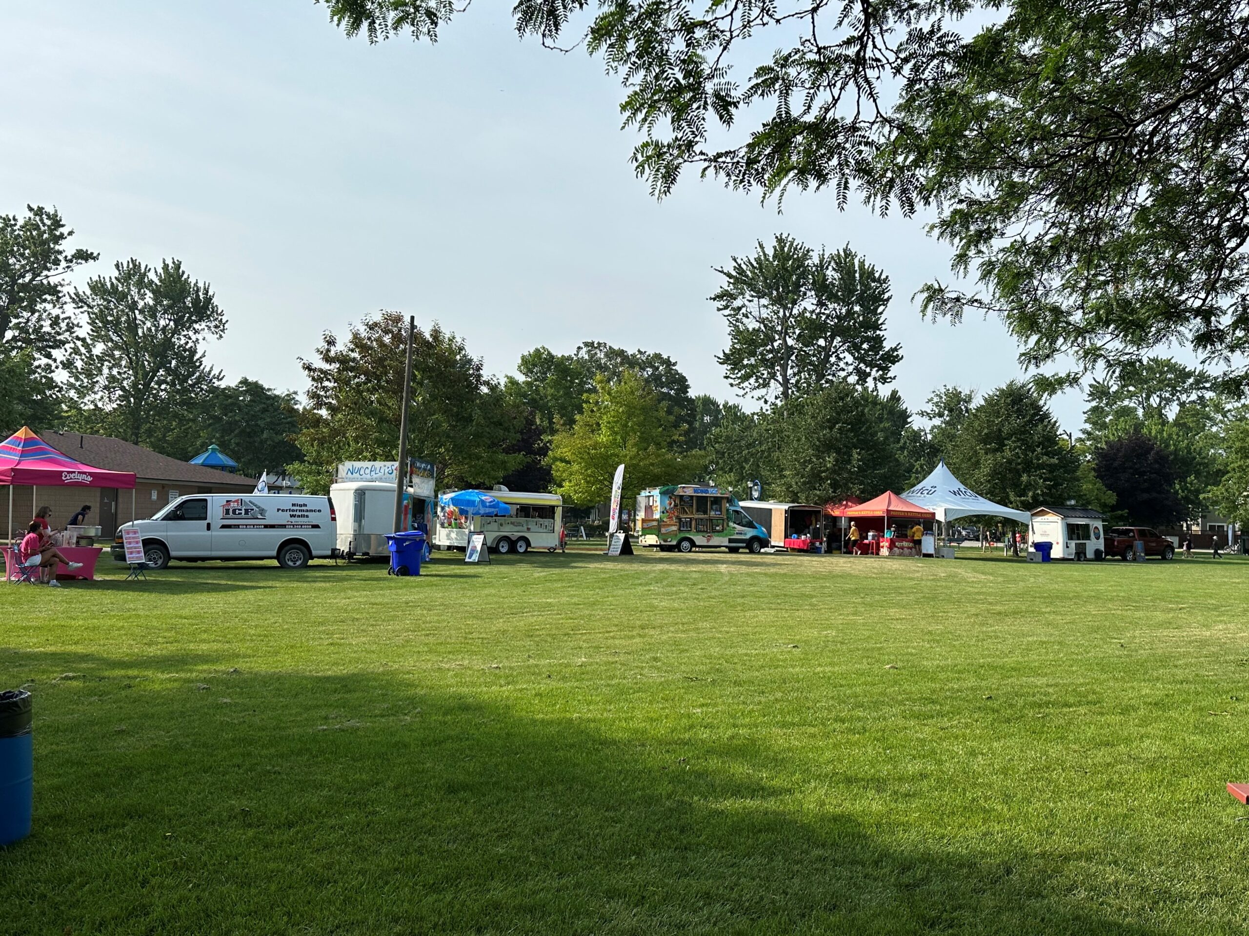 line of different food trucks on the grass