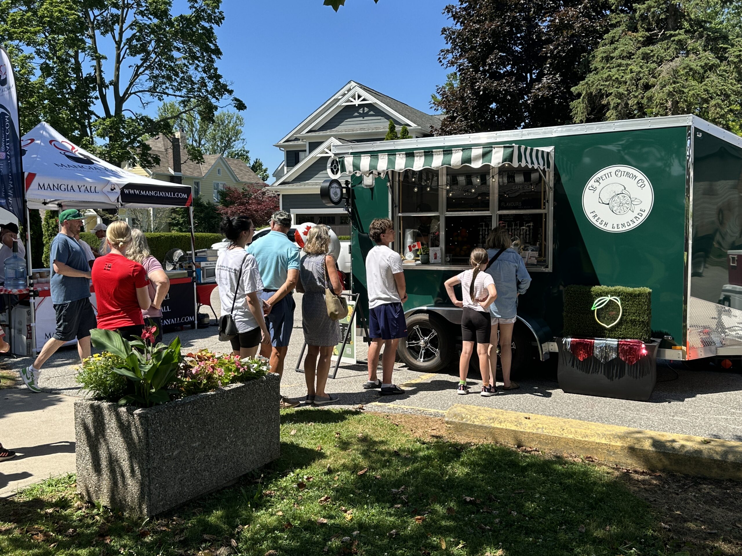 People waiting in line at a food truck parked on the street.