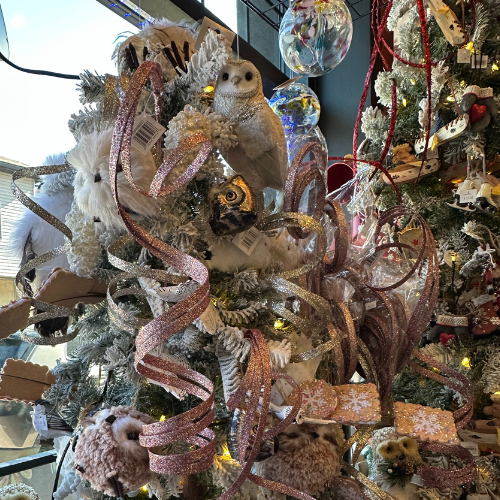 Christmas tree featuring lights, pink ribbon and snowy owl ornaments