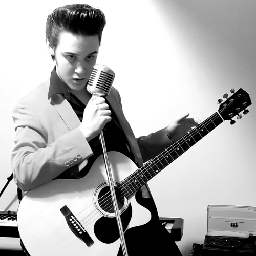 black and white guy (Nick Robinson) with guitar and mic