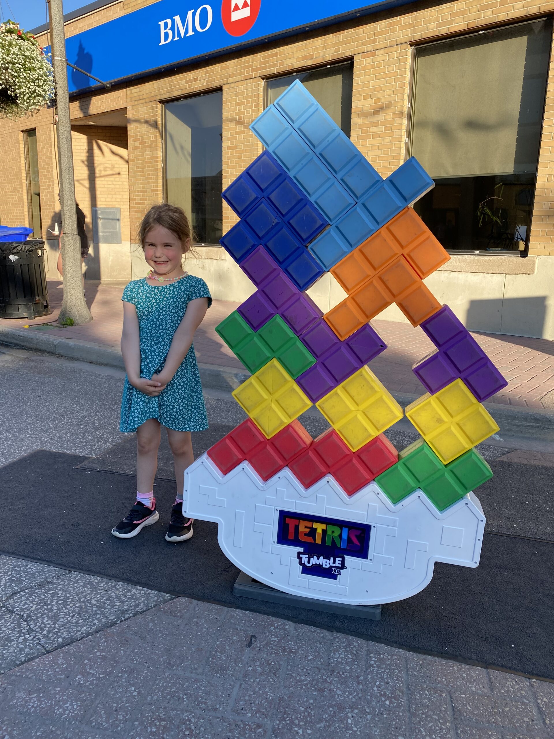 Young girl smiling while standing beside jumbo Tetris game during Open Air